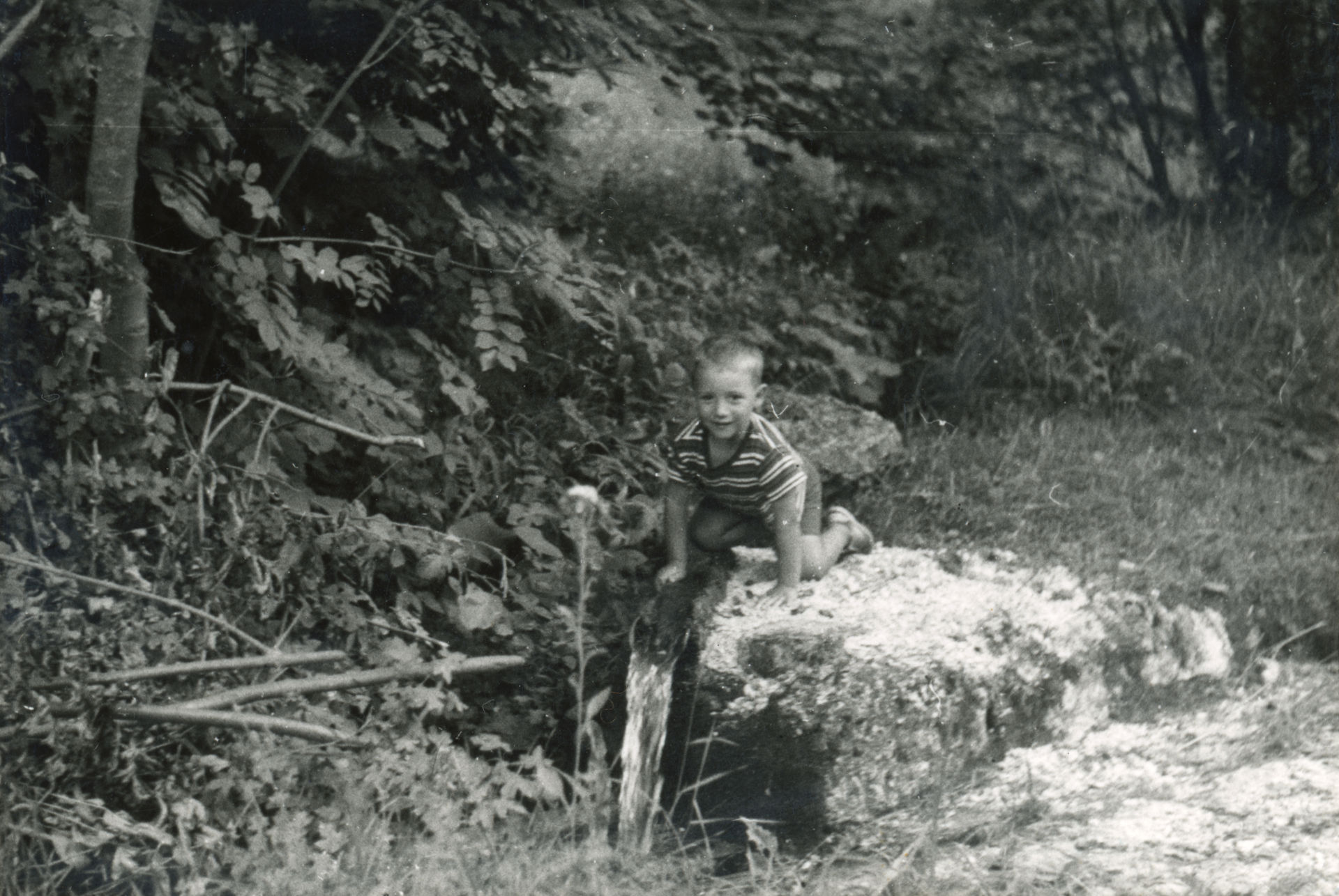 Un bambino vicino a una sorgente d'acqua