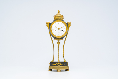 An elegant French Neoclassical patinated and gilt bronze mantel clock with mascarons, 19th C.