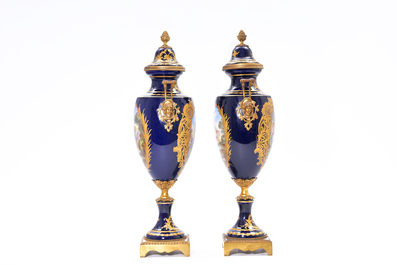Een paar Franse goudgehoogde dekselvazen met blauwe fondkleur en liefdessc&egrave;nes door Bertre, gemerkt Ch&acirc;teau des Tuileries en S&egrave;vres, ca. 1900