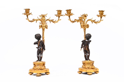 A pair of French patinated and gilt bronze three-light candlesticks in the form of a putto carrying a bouquet of flowers, 19th C.