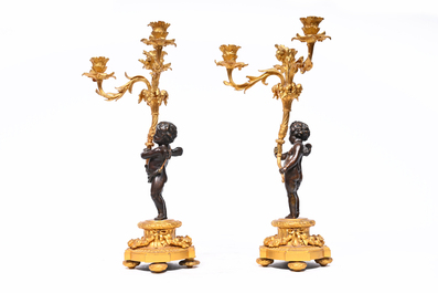 A pair of French patinated and gilt bronze three-light candlesticks in the form of a putto carrying a bouquet of flowers, 19th C.