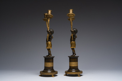 Een paar Franse verguld en gepatineerd bronzen Directoire kandelaars met twee lichtpunten in de vorm van toortsdragende Afrikanen, eind 18de eeuw