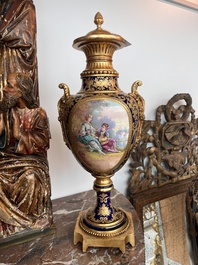 Paire de vases couvertes &agrave; fond bleu royale &agrave; la mani&egrave;re de S&egrave;vres aux montures dor&eacute;es et &agrave; d&eacute;cor de sc&egrave;ne d'amour, France, 20&egrave;me si&egrave;cle