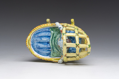 A polychrome Dutch Delft model of a cradle with child, 19th C.