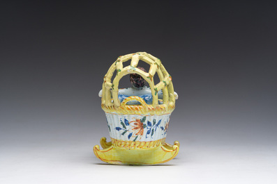 A polychrome Dutch Delft model of a cradle with child, 19th C.