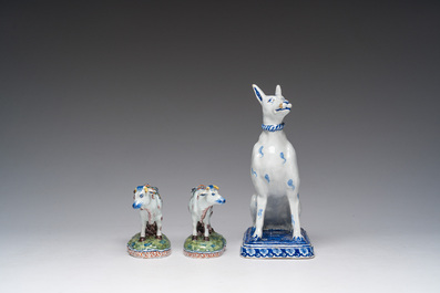A blue and white Dutch Delft model of a seated dog and a pair of polychrome cows, 19th C.