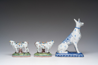 A blue and white Dutch Delft model of a seated dog and a pair of polychrome cows, 19th C.
