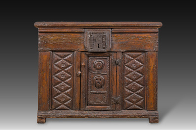 A carved oak one-door cupboard with the central panel carved with two heads, probably Germany, 16th C.