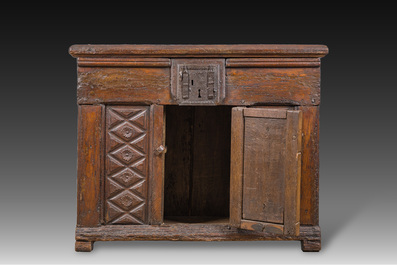 A carved oak one-door cupboard with the central panel carved with two heads, probably Germany, 16th C.