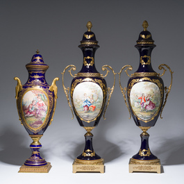 Three French gold layered blue ground gilt bronze mounted S&egrave;vres style vases and covers with gallant scenes, 20th C.