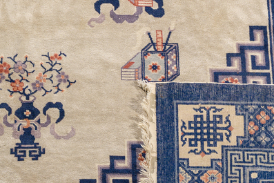 A Chinese Beijing rug with antiquities, floral design and stylized motifs, wool on cotton, 20th C.