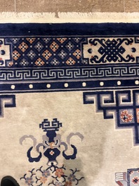 A Chinese Beijing rug with antiquities, floral design and stylized motifs, wool on cotton, 20th C.