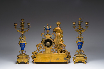 Een Franse driedelige schouwgarnituur in verguld brons bekroond met een dame met een juwelenkoffer in de hand, 19de eeuw