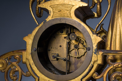 Een Franse driedelige schouwgarnituur in verguld brons bekroond met een dame met een juwelenkoffer in de hand, 19de eeuw