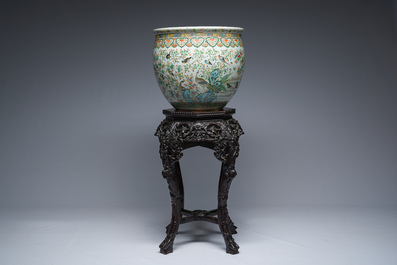 A Chinese famille rose jardini&egrave;re with birds on blossoming branches on an open worked carved wooden stand with marble top, 19th/20th C.