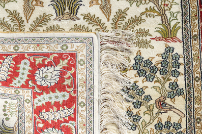 A Chinese silk Hereke style rug with birds among blossoming branches, 20th C.