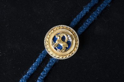 An 18 carat white and yellow gold Texan tie with a capricorn finished with diamonds (0,15 carat) and lapis lazuli, 20th C.