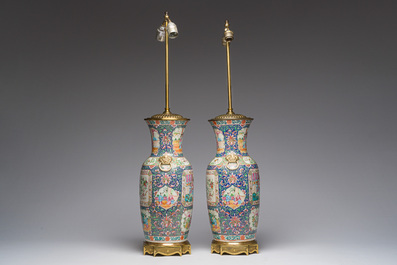 Een paar Chinese Kanton famille rose vazen met blauwe fondkleur, paleissc&egrave;nes en floraal decor omgevormd tot lampen, 19de eeuw