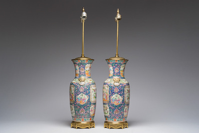 Een paar Chinese Kanton famille rose vazen met blauwe fondkleur, paleissc&egrave;nes en floraal decor omgevormd tot lampen, 19de eeuw
