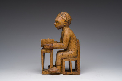 Sculpture en bois sculpt&eacute; d'un homme assis &agrave; un bureau avec un livre &agrave; la main, Bakongo, Congo, premier tiers du 20&egrave;me si&egrave;cle