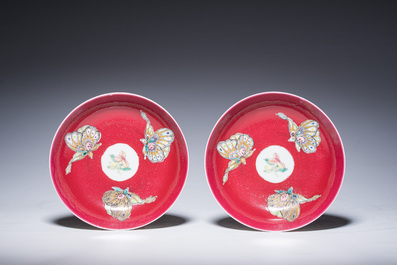 Een paar Chinese famille rose schotels met vlinders op een robijnrode fondkleur, 19de/20ste eeuw