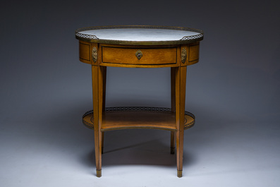 An oval French Louis XVI wooden writing table with gilt copper and brass mounts and a marble top, circa 1800