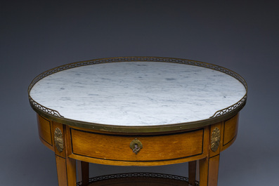 An oval French Louis XVI wooden writing table with gilt copper and brass mounts and a marble top, circa 1800