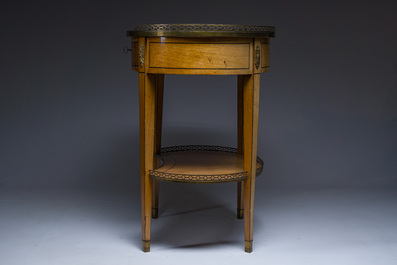 An oval French Louis XVI wooden writing table with gilt copper and brass mounts and a marble top, circa 1800