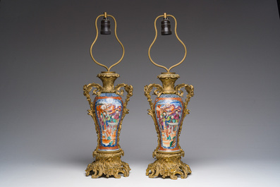 Een paar Chinese famille rose vazen met mandarijns decor met verguld bronzen monturen omgevormd tot lampen, Qianlong