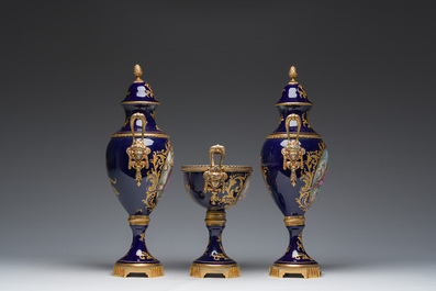 Een driedelige Franse S&egrave;vres-stijl schouwgarnituur met blauwe fondkleur, verguld bronzen monturen en galante sc&egrave;nes, 20ste eeuw