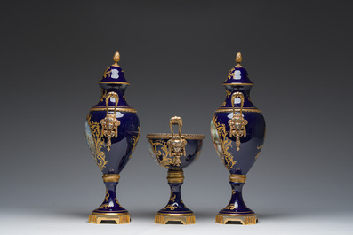Een driedelige Franse S&egrave;vres-stijl schouwgarnituur met blauwe fondkleur, verguld bronzen monturen en galante sc&egrave;nes, 20ste eeuw
