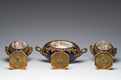 Een driedelige Franse S&egrave;vres-stijl schouwgarnituur met blauwe fondkleur, verguld bronzen monturen en galante sc&egrave;nes, 20ste eeuw
