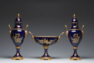 Een driedelige Franse S&egrave;vres-stijl schouwgarnituur met blauwe fondkleur, verguld bronzen monturen en galante sc&egrave;nes, 20ste eeuw