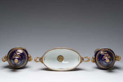 Een driedelige Franse S&egrave;vres-stijl schouwgarnituur met blauwe fondkleur, verguld bronzen monturen en galante sc&egrave;nes, 20ste eeuw