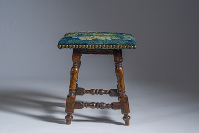 A wooden stool with turned legs upholstered with a fragment of a Flemish wall tapestry, 17th C.