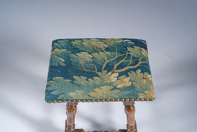 A wooden stool with turned legs upholstered with a fragment of a Flemish wall tapestry, 17th C.