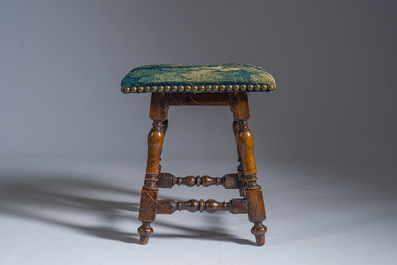 A wooden stool with turned legs upholstered with a fragment of a Flemish wall tapestry, 17th C.