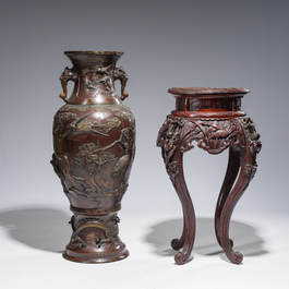 A large Japanese bronze vase with relief design of cranes, dragons and birds on a wooden stand with floral design, Meiji, 19th/20th C.