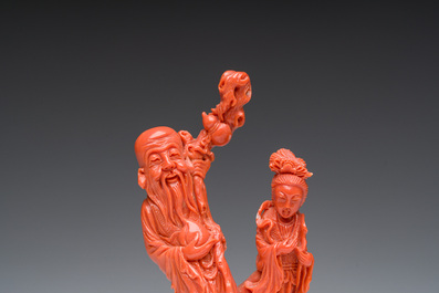 A Chinese red coral group with the 'Star God' Shou Xing and a lady, 19th/20th C.