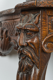 A large carved wooden 'Black Forest' clock with a deer hunt on a console tabel with floral design, 19th/20th C.