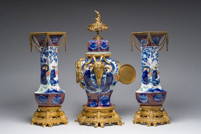 A Japanese polychrome three-piece garniture with ladies in a landscape mounted into a clock with richly gilt bronze mounts, 19th C.