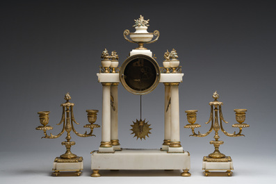 A French Louis XVI style three-piece gilt bronze mounted white marble clock garniture crowned with a flower basket, 19th C.