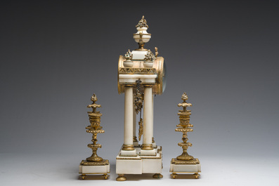A French Louis XVI style three-piece gilt bronze mounted white marble clock garniture crowned with a flower basket, 19th C.