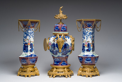 A Japanese polychrome three-piece garniture with ladies in a landscape mounted into a clock with richly gilt bronze mounts, 19th C.