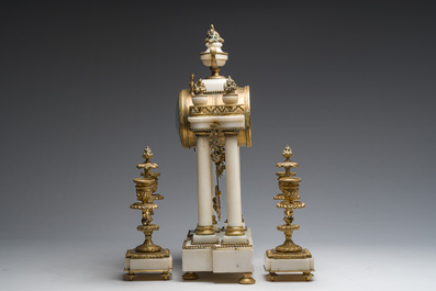 A French Louis XVI style three-piece gilt bronze mounted white marble clock garniture crowned with a flower basket, 19th C.