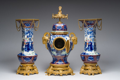 A Japanese polychrome three-piece garniture with ladies in a landscape mounted into a clock with richly gilt bronze mounts, 19th C.