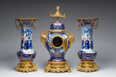 A Japanese polychrome three-piece garniture with ladies in a landscape mounted into a clock with richly gilt bronze mounts, 19th C.
