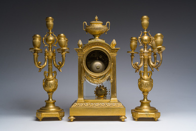 A French Louis XVI style gilt bronze and cut glass mantel clock accompanied by a pair of candlesticks, 19th/20th C.