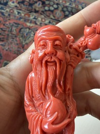 A Chinese red coral group with the 'Star God' Shou Xing and a lady, 19th/20th C.