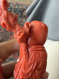A Chinese red coral group with the 'Star God' Shou Xing and a lady, 19th/20th C.